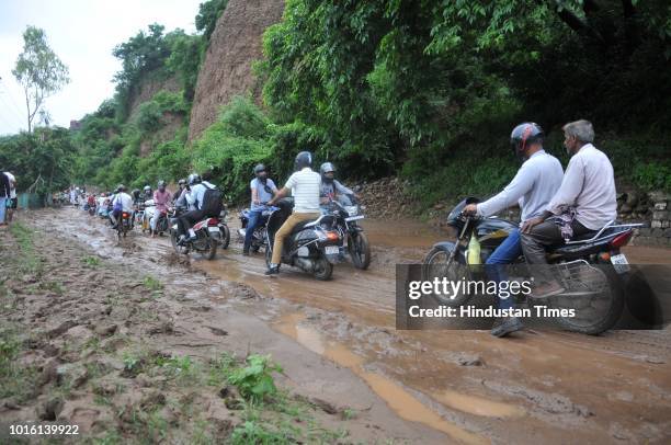 Commuters pass through a road hit by a landslide after heavy rains at Byepass road on August 13, 2018 in Jammu, India.