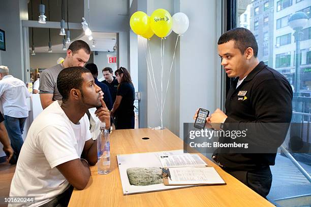 Sprint employee Ozzie Cux, right, instructs Rondy Ferrier on how to use his new HTC Corp. 4G Evo phone, which is powered by Google Inc.'s Android...