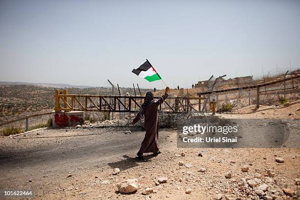 Palestinian woman waves the Palestinian national flag near an Israeli barrier, against Israel's attack on the flotilla earlier this week, on June 4,...