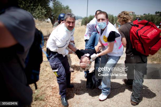 Palestinians evacuate a woman after she inhaled tear gas near an Israeli barrier, as they object to Israel's attack on a Gaza aid flotilla earlier...