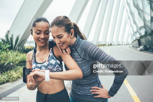 runner girls watching a smart watch after run - singapore racing stock pictures, royalty-free photos & images