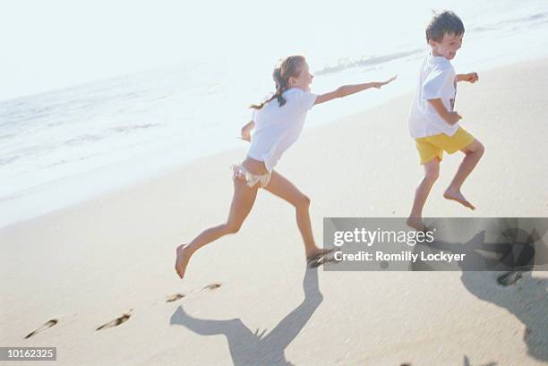 boy playing on the beach with waves - kids playing tag fotografías e imágenes de stock