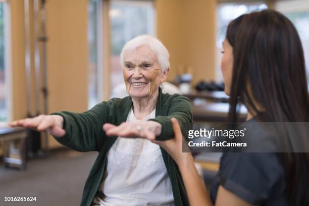 senior mujer trabaja con su terapeuta ocupacional - geriatria fotografías e imágenes de stock