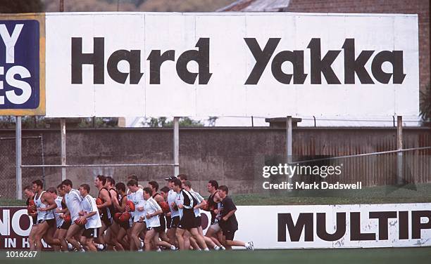 Collingwood players run laps past a "hard yakka" sign at a Collingwood Pre Season training session, held at Victoria Park, Melbourne, Australia....
