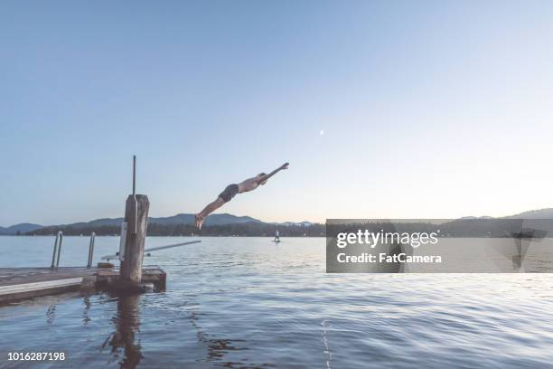 young man dives into a lake off pier at dusk - 2017 usa diving summer stock pictures, royalty-free photos & images