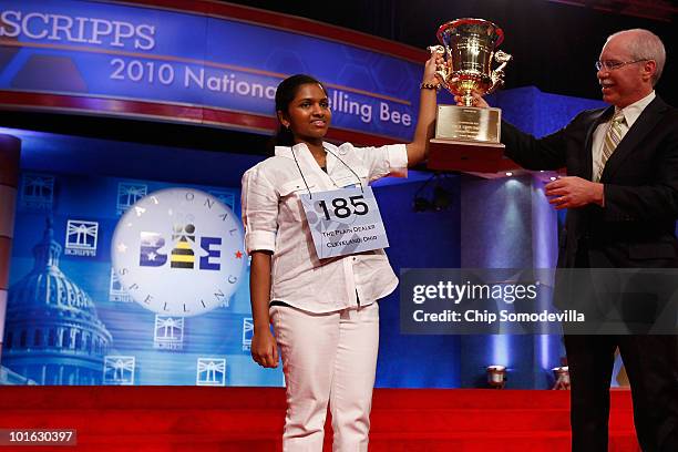 Fourteen-year-old Speller No. 185, Anamika Veeramani of Cleveland, Ohio, is handed her championship trophy by Scripps CEO Rich Boehne after winning...