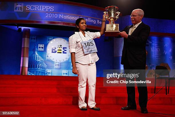 Fourteen-year-old Speller No. 185, Anamika Veeramani of Cleveland, Ohio, is handed her championship trophy by Scripps CEO Rich Boehne after winning...
