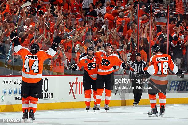 Jeff Carter of the Philadelphia Flyers celebrates with teammates Kimmo Timonen, Simon Gagne and Mike Richards after scoring an empty-net goal in the...