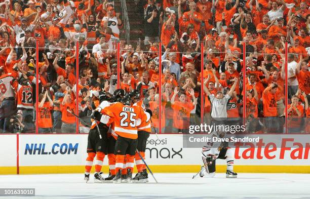 Nick Boynton of the Chicago Blackhawks kneels dejected as Ville Leino and Daniel Briere of the Philadelphia Flyers celebrate Leino's goal in the...