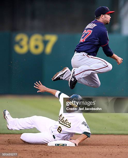 Hardy of the Minnesota Twins leaps over Kurt Suzuki of the Oakland Athletics on a double play hit by Jack Cust in the fourth inning during an MLB...