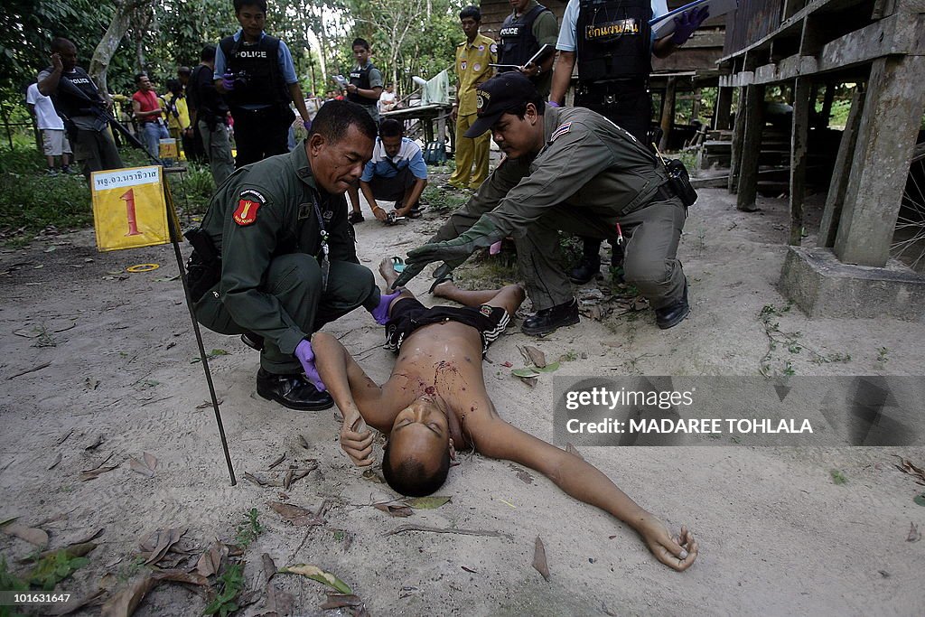 Thai police officers inspect the body of