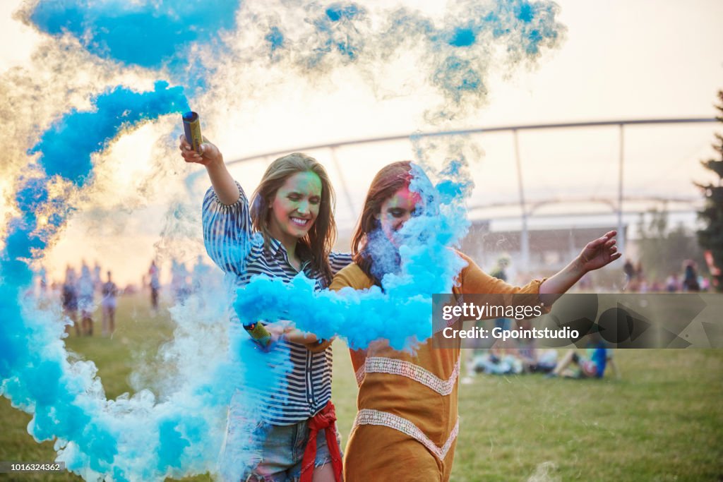 Two young women dancing with blue smoke bombs at Holi Festival