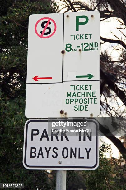 signs stating 'no stopping', that parking tickets are required from 8 am to midnight, the ticket machine is on the opposite side and 'park in bays only' - parking ticket stock pictures, royalty-free photos & images