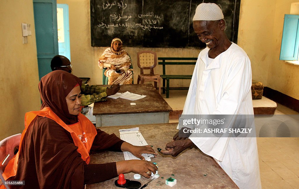 A Sudanese man dips his finger in ink as