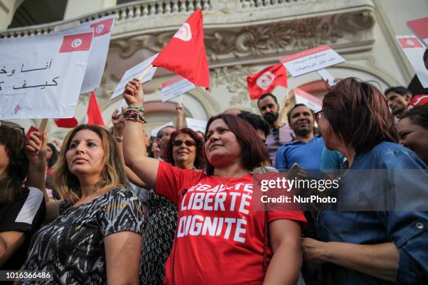 Woman wearing a shirt which reads 'equality, freedom, dignity' waves the flag of Tunisia during the celebration of the National Womens Day in avenue...