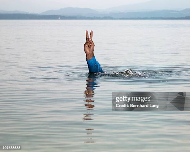hand making victory sign in lake - appearance foto e immagini stock