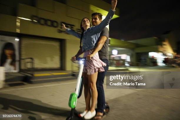 Man and woman ride a shared dockless electric scooter along Venice Beach on August 13, 2018 in Los Angeles, California. Shared e-scooter startups...