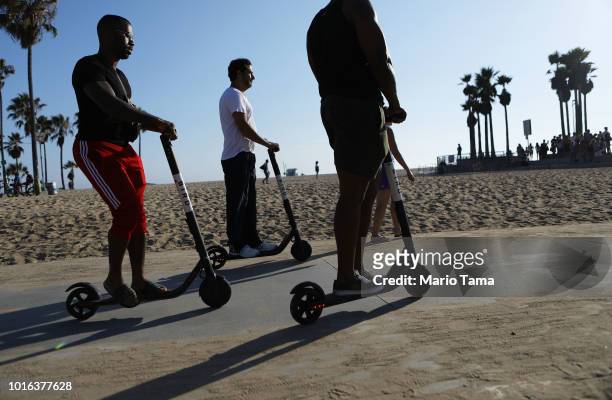 People ride Bird shared dockless electric scooters along Venice Beach on August 13, 2018 in Los Angeles, California. Shared e-scooter startups Bird...