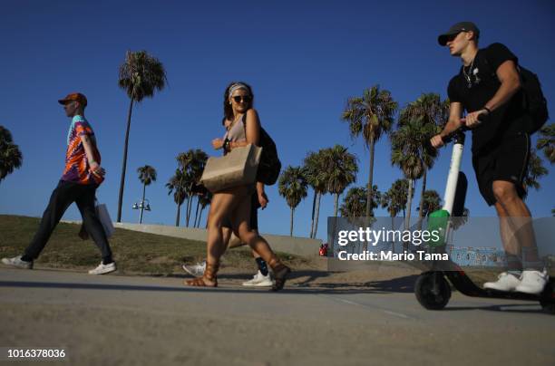 Man rides a Lime shared dockless electric scooter along Venice Beach on August 13, 2018 in Los Angeles, California. Shared e-scooter startups Bird...