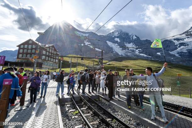 Tourists follow their guide prior to embark at Kleine Scheidegg train station the Jungfraubahn for their trip at the Jungfraujoch, 3500 meters high...