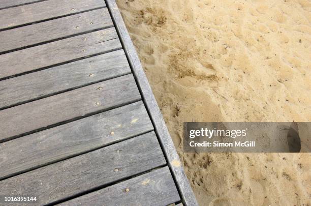 wooden boardwalk at a sandy beach - holzsteg stock-fotos und bilder