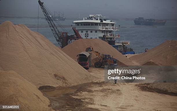 Workers unload sand from a ship at a land reclamation site of the Tanggu Coastal Economic Zone on June 5, 2010 in Tanggu of Tianjin Municipality,...