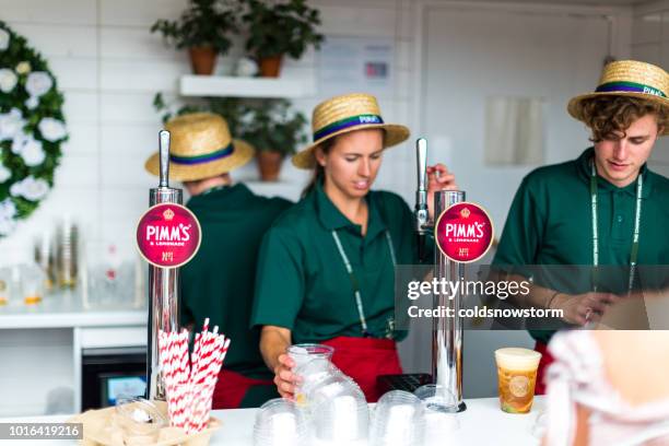 young bartenders serving pimm's on tap at pop-up bar, london, uk - pop up store stock pictures, royalty-free photos & images