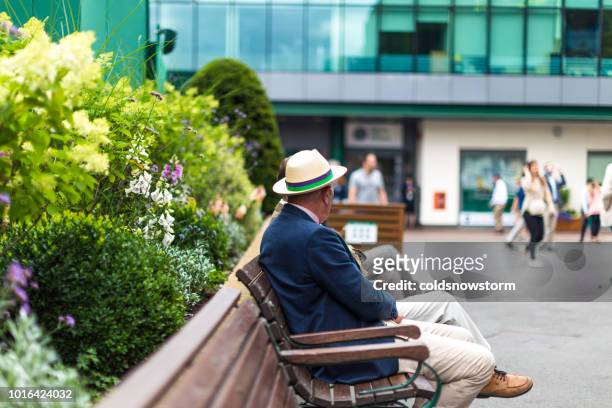 senior man zit op de bank met stro boater hoed, wimbledon, verenigd koninkrijk - the championships wimbledon 2018 stockfoto's en -beelden