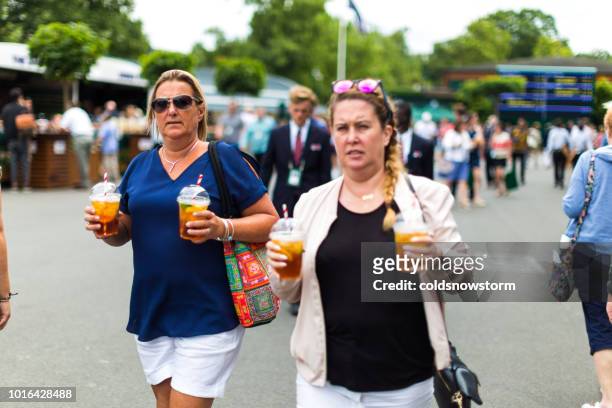 women carrying plastic cups of pimm's outdoors, wimbledon, uk - the championships wimbledon 2018 stock pictures, royalty-free photos & images