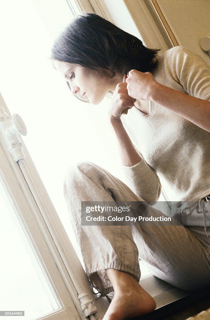 YOUNG WOMAN LOOKING THROUGH WINDOW