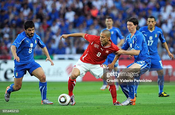 Gokhan Inler of Switzerland is challenged by Gennaro Gattuso and Riccardo Montolivo of Italy during the international friendly match between...