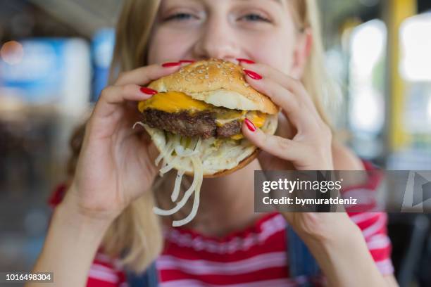 frau essen beef-burger - cholesterin stock-fotos und bilder