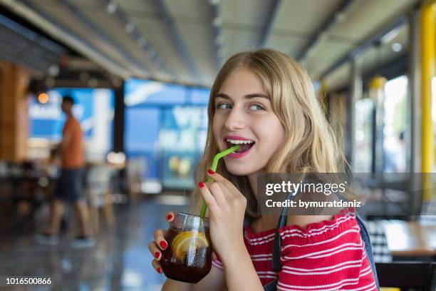 young woman drinks coke in a cafe - cola stock pictures, royalty-free photos & images