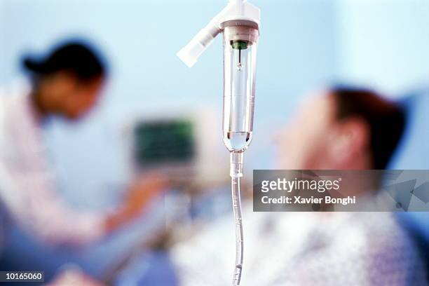 man in hospital bed, nurse checks monitor - infuus stockfoto's en -beelden