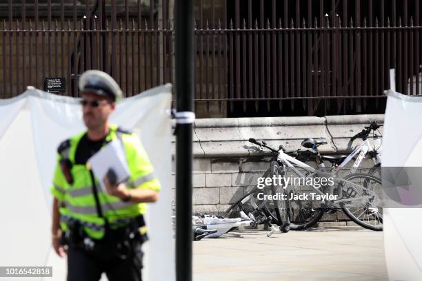 Police officers stand guard near bicycles believed to have been damaged when a vehicle crashed into security barriers this morning outside the Houses...