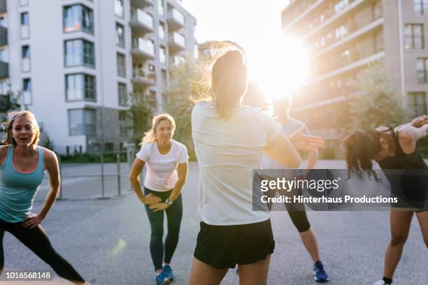 fitness instructor warming up with class outdoors - sports training stock-fotos und bilder