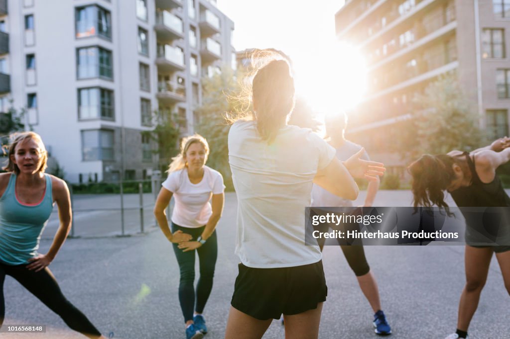 Fitness Instructor Warming Up With Class Outdoors