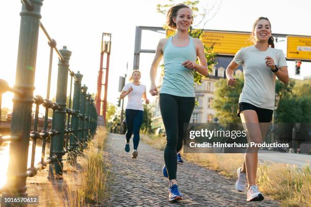 female fitness group running alongside canal - gray shorts stock pictures, royalty-free photos & images