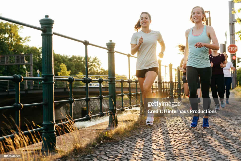 Group Of Women Running Together Alongside Canal