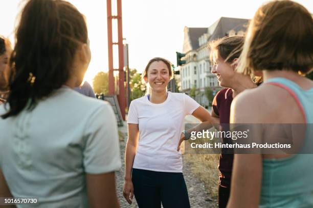 group of women chatting before city run together - gruppen im kreis stock-fotos und bilder