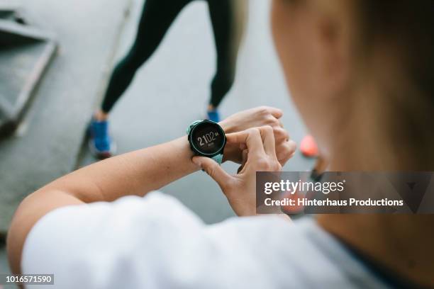 fitness enthusiast setting timer on her watch - wristwatch fotografías e imágenes de stock