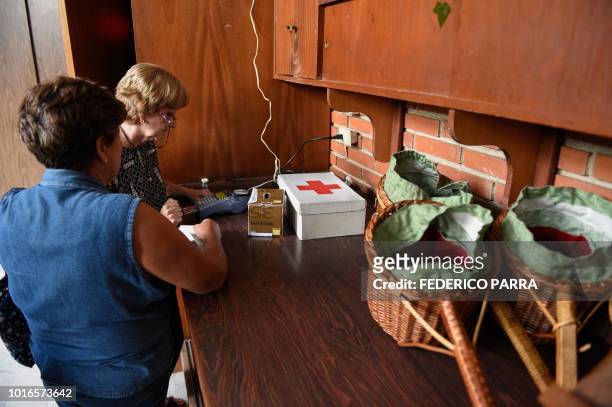 Catholic faithful pays the tithe with a debit card at La Coromoto Church, in Caracas on August 12, 2018. - The shortage of cash in the country has...