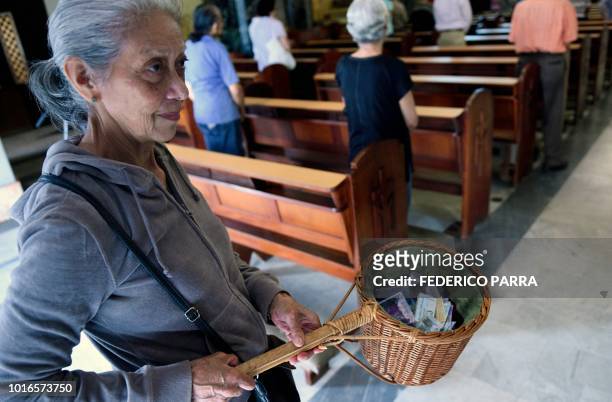 Volunteer collects the tithe during a mass at La Coromoto Church, in Caracas on August 12, 2018. - The shortage of cash in the country has forced...