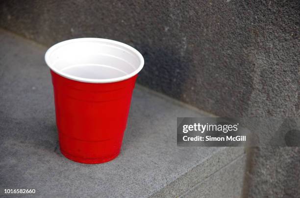 red and white plastic cup on an inner city doorstep - red cup stock pictures, royalty-free photos & images