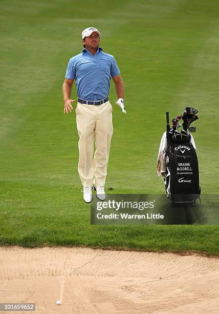 Graeme McDowell of Northern Ireland jumps to see the line of his shot out of the fairway bunker on the seond hole during the final round of the...