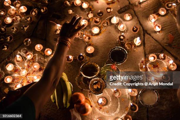 woman arranging oil lamps during diwali at ghats of ganga in varanasi, india - offerta religiosa foto e immagini stock