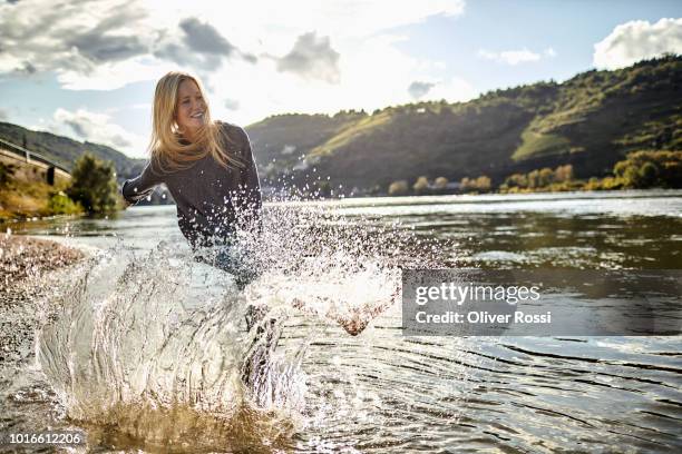 young woman in a river splashing water - wading river stock pictures, royalty-free photos & images