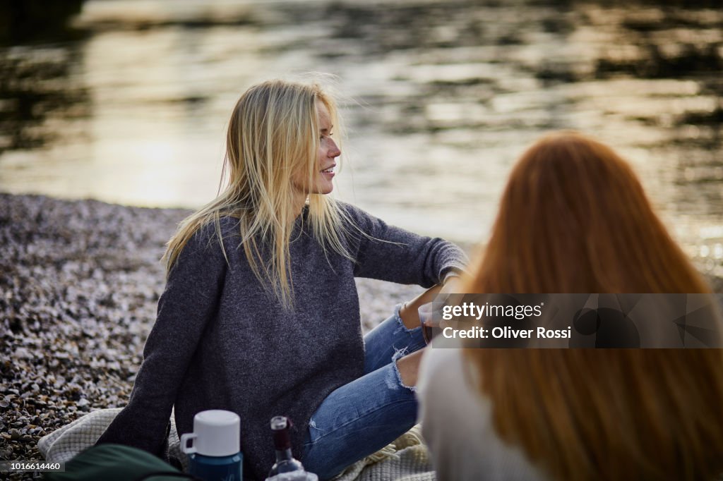 Two female friends having a picnic at the riverbank