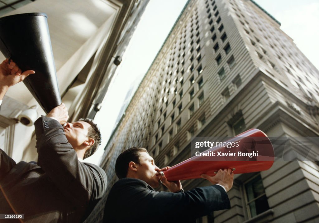 TWO BUSINESSMEN ON SIDEWALK WITH BULLHORNS