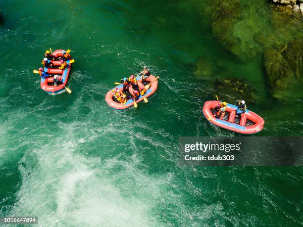 Aerial view of a group of men and women in multiple boats white water river rafting